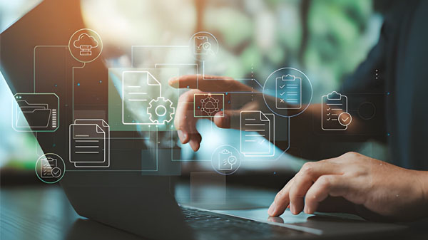 Seorang individu sedang menggunakan laptop dengan ikon digital melayang di atas layar, termasuk folder, dokumen, awan penyimpanan, daftar centang, roda gigi, dan koneksi jaringan—melambangkan manajemen data dan alur kerja digital dalam suasana profesional yang terang dan modern.